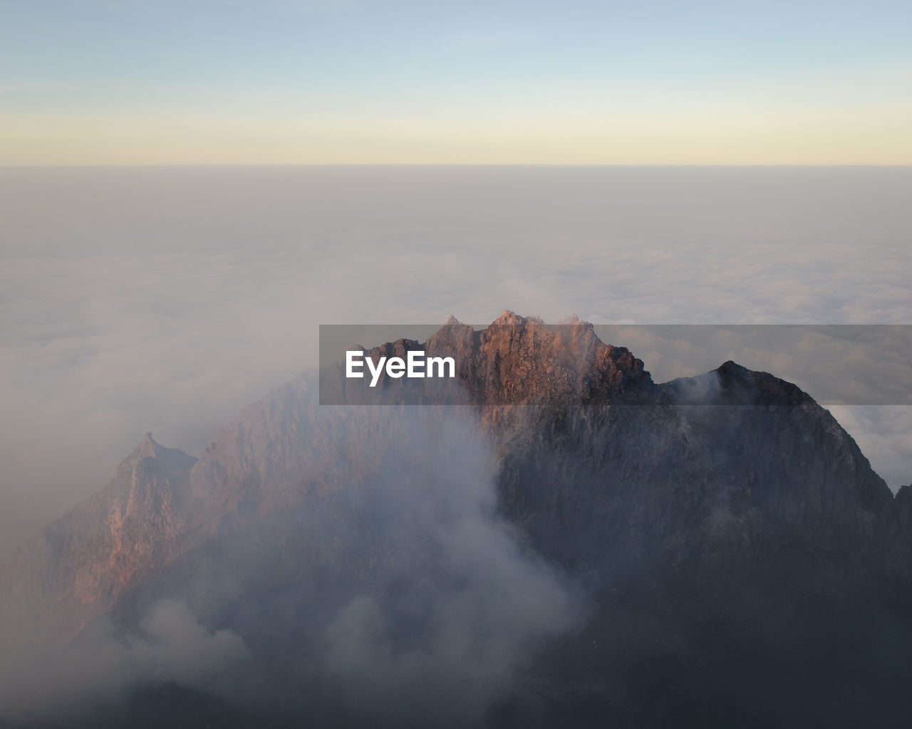 Scenic view of mountain covered in fog against sky 