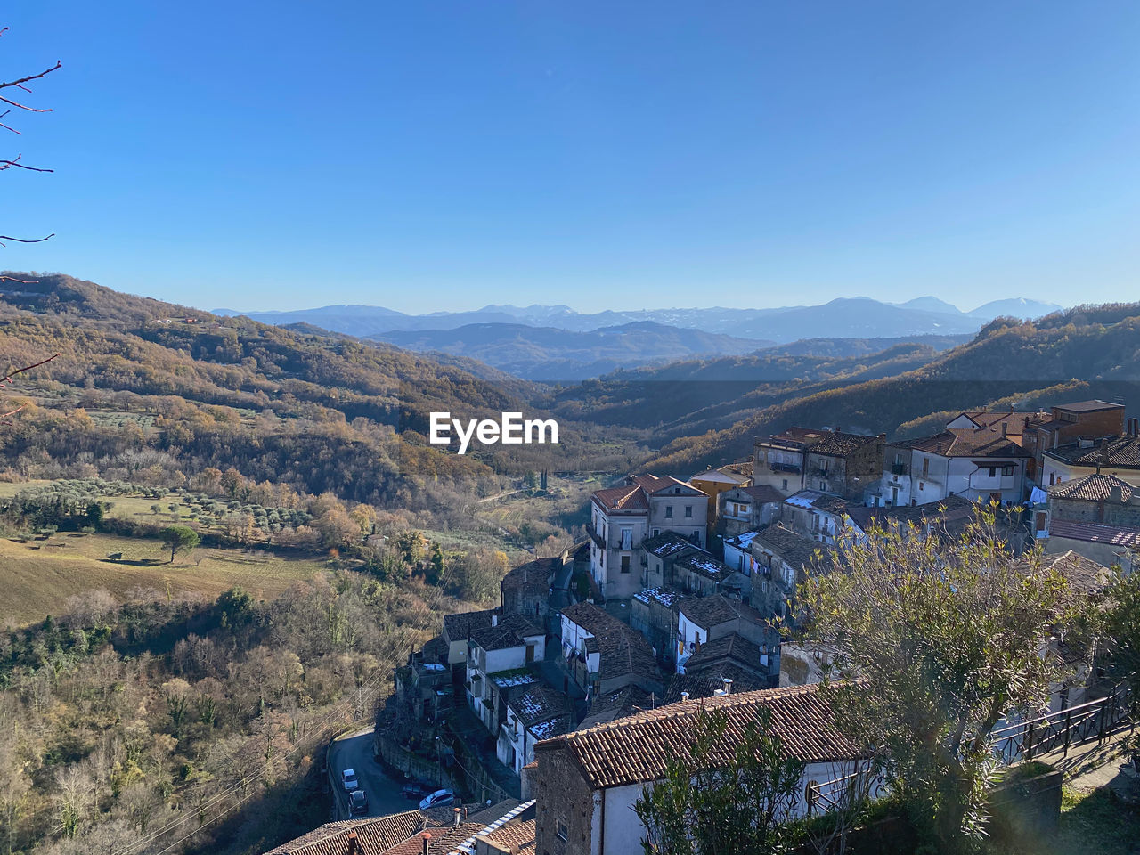 Aerial view of townscape by mountains against clear blue sky