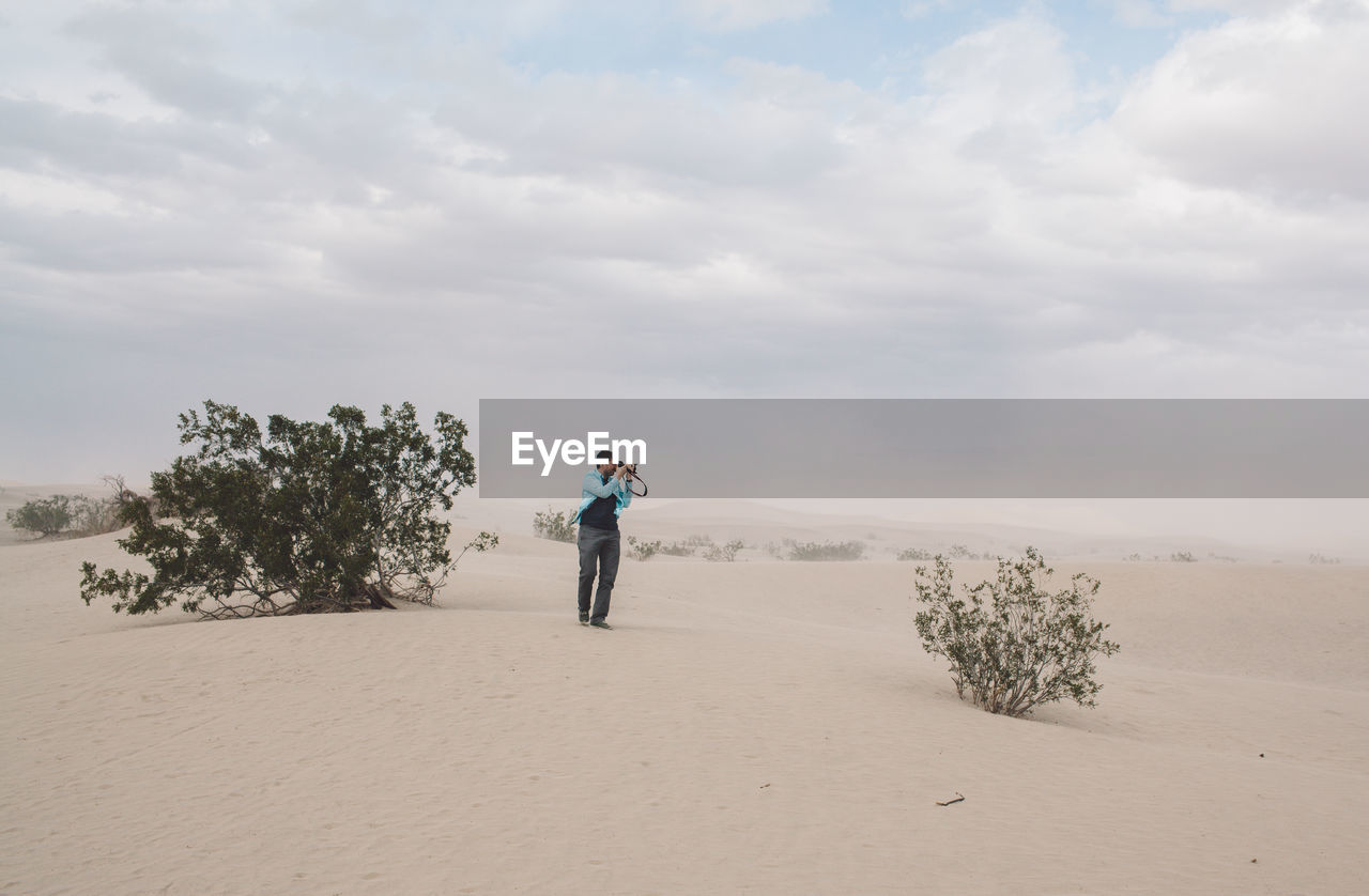 Full length of man photographing in desert