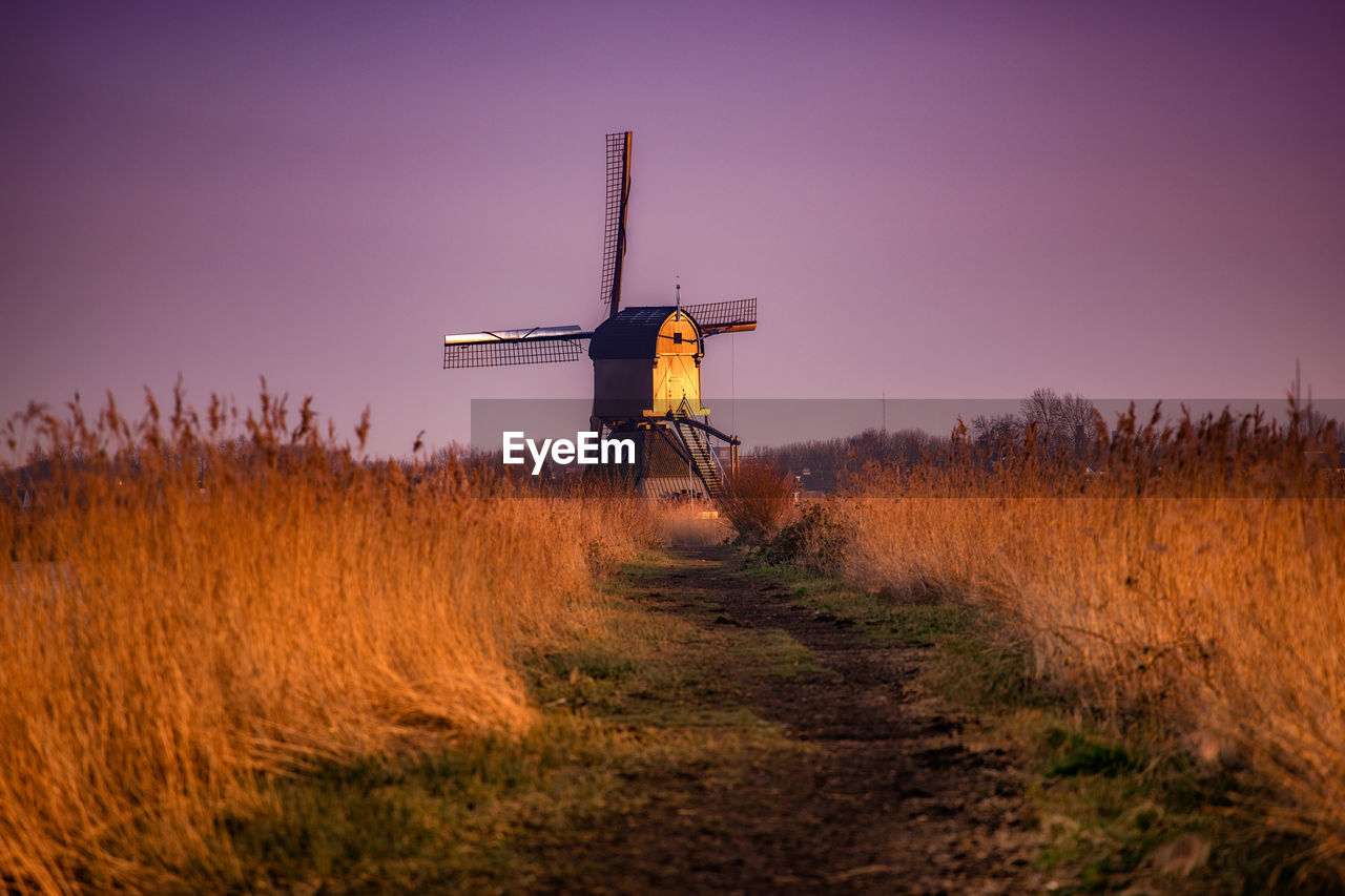 Traditional windmill on field during sunset