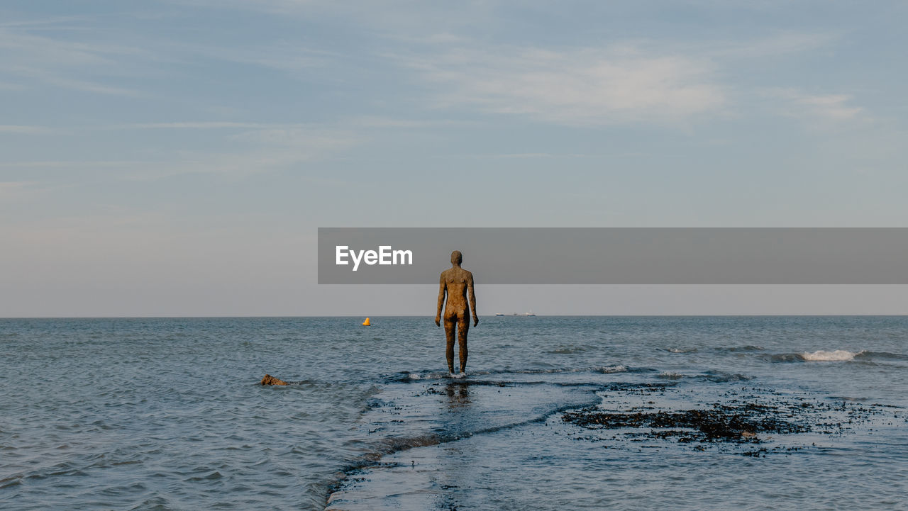 The sea tide partially submerges human figure of the another time statue by artist anthony gormley 