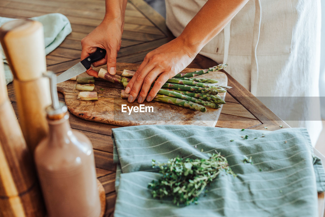 Female hands cutting asparagus on a cutting board on a table