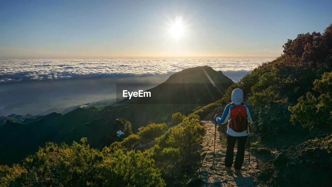 Rear view of woman standing on mountain against sky during sunrise