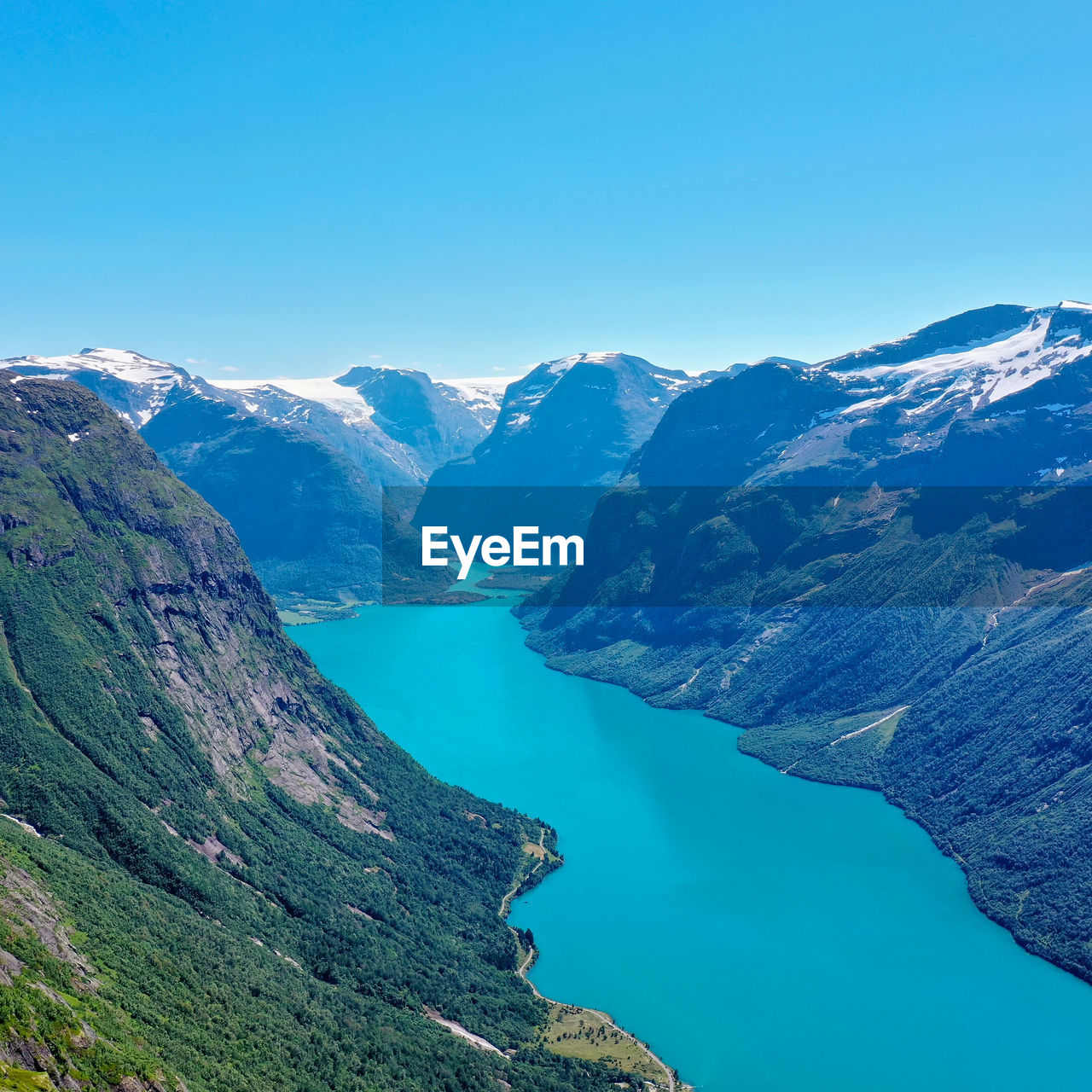 Scenic view of lake and mountains against clear blue sky