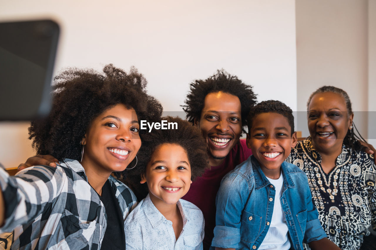 Smiling woman taking selfie with family at home