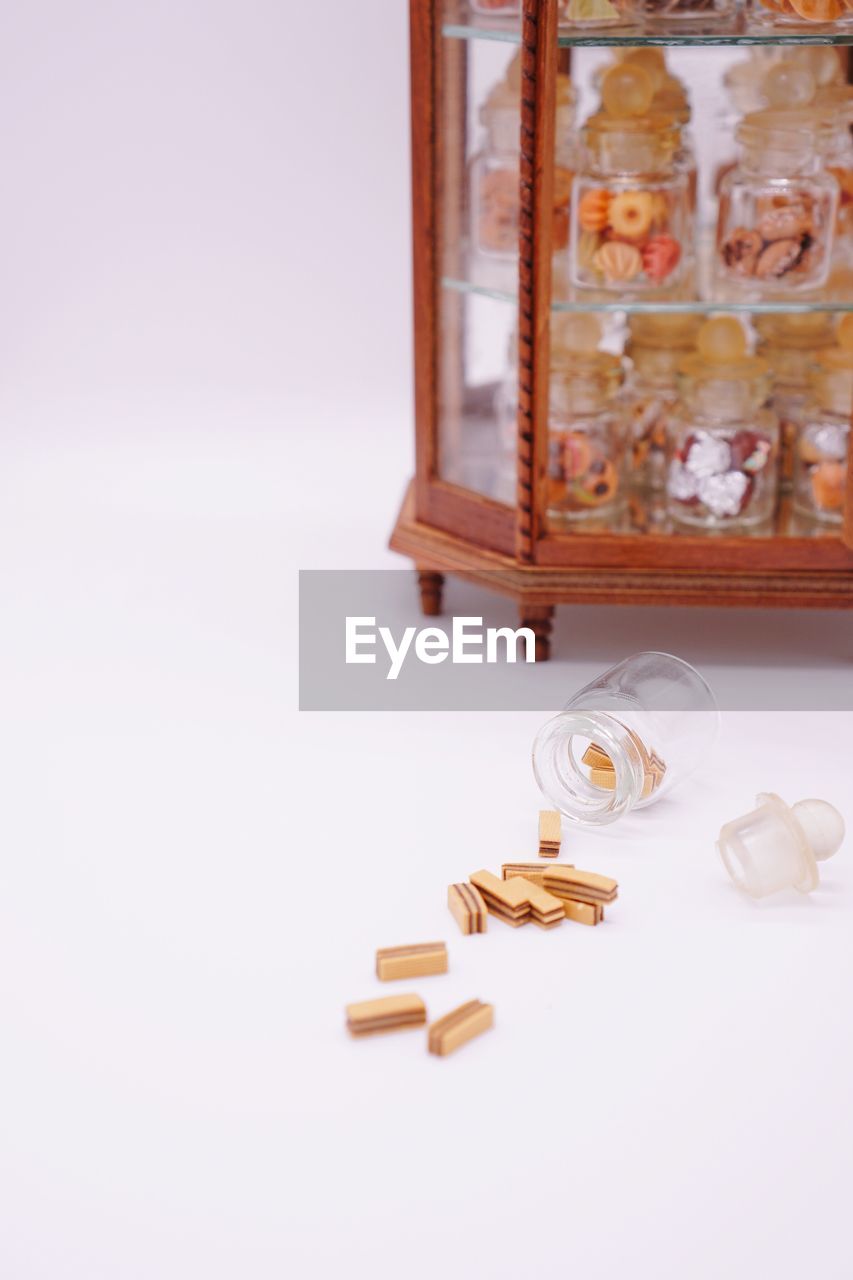 Close-up of glass jars in cabinet against white background