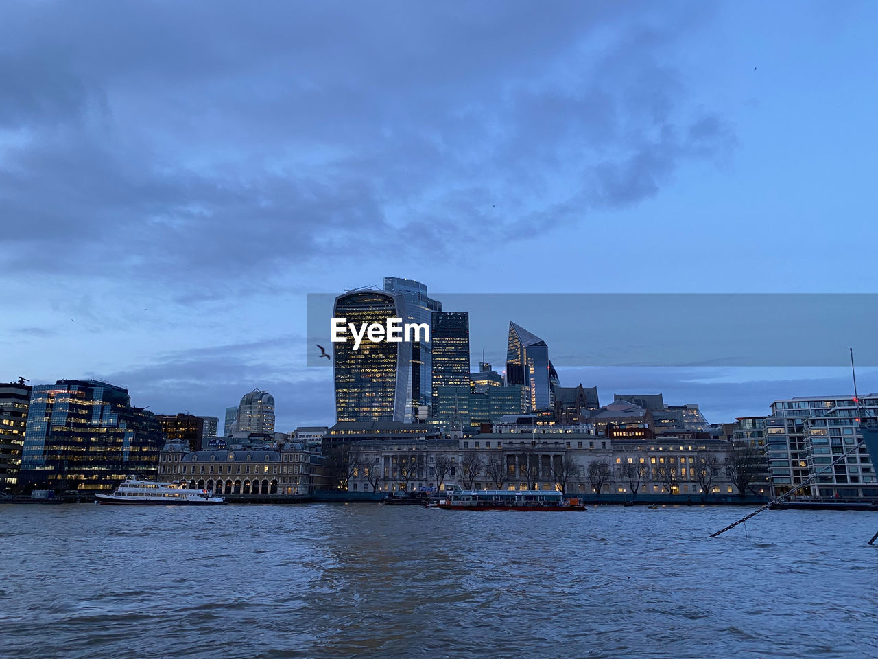 View across river thames to city of london at dusk