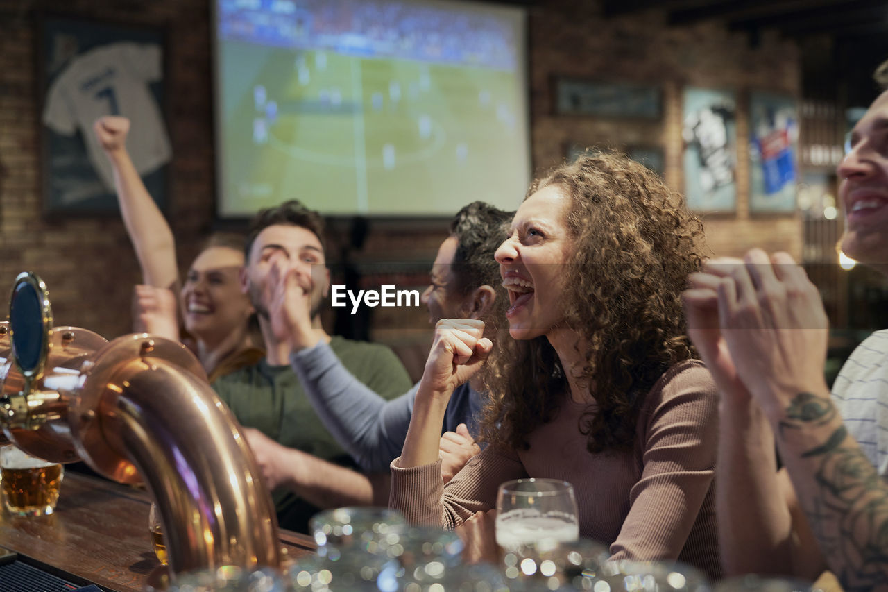 Happy friends watching soccer match at bar