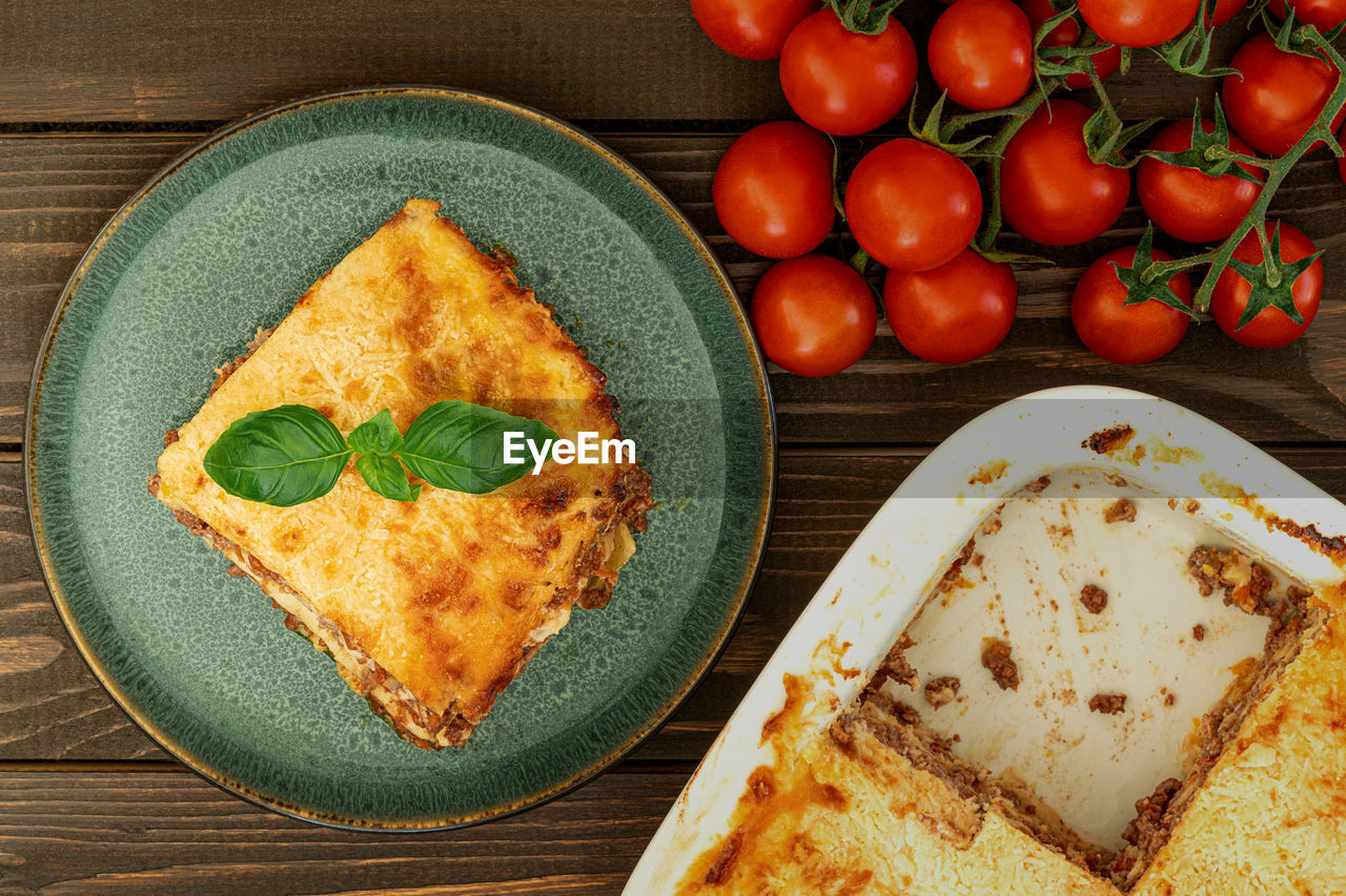 Classic italian lasagna piece at plate on wooden table from above, healthy food