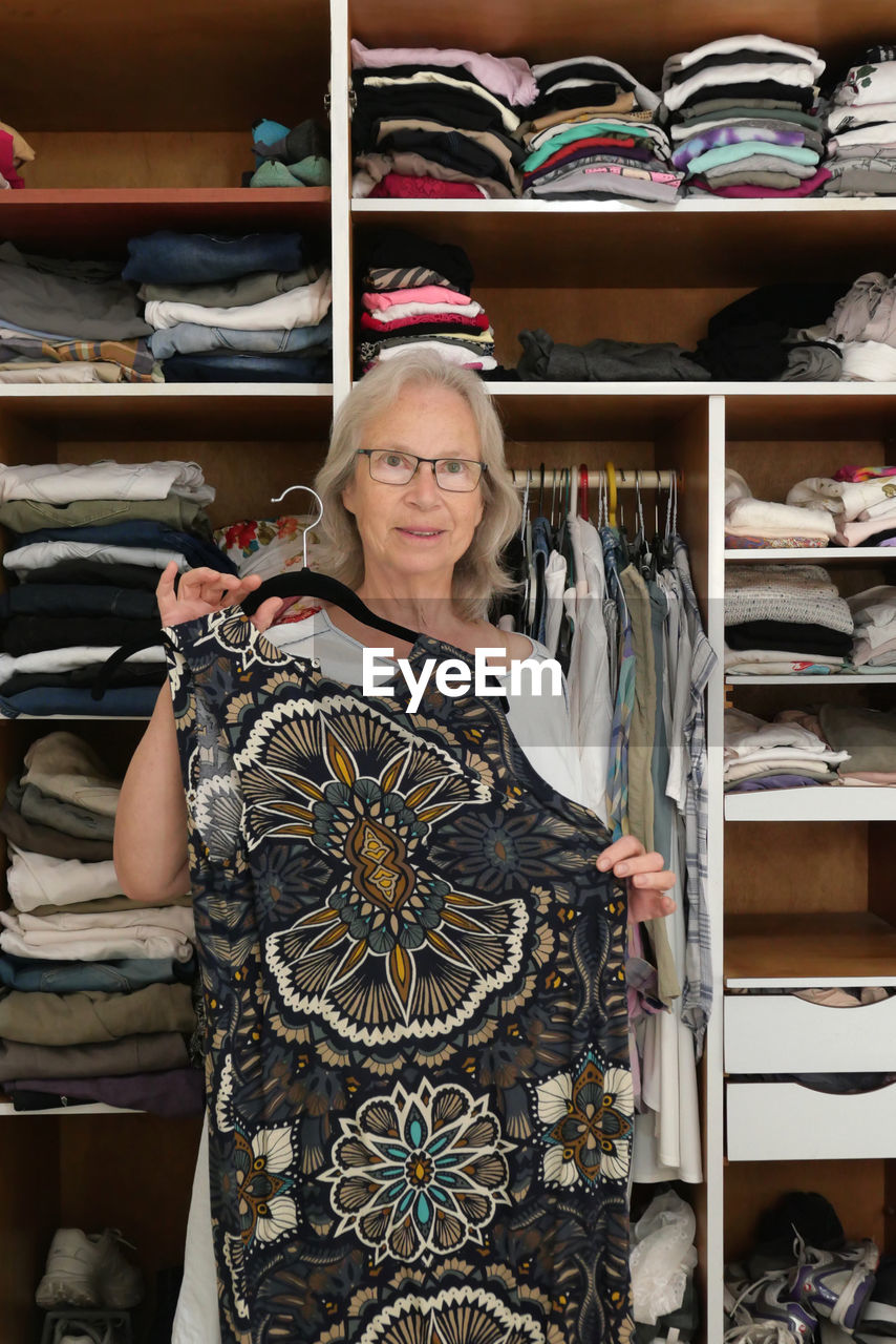 Senior woman choosing dress in her room 