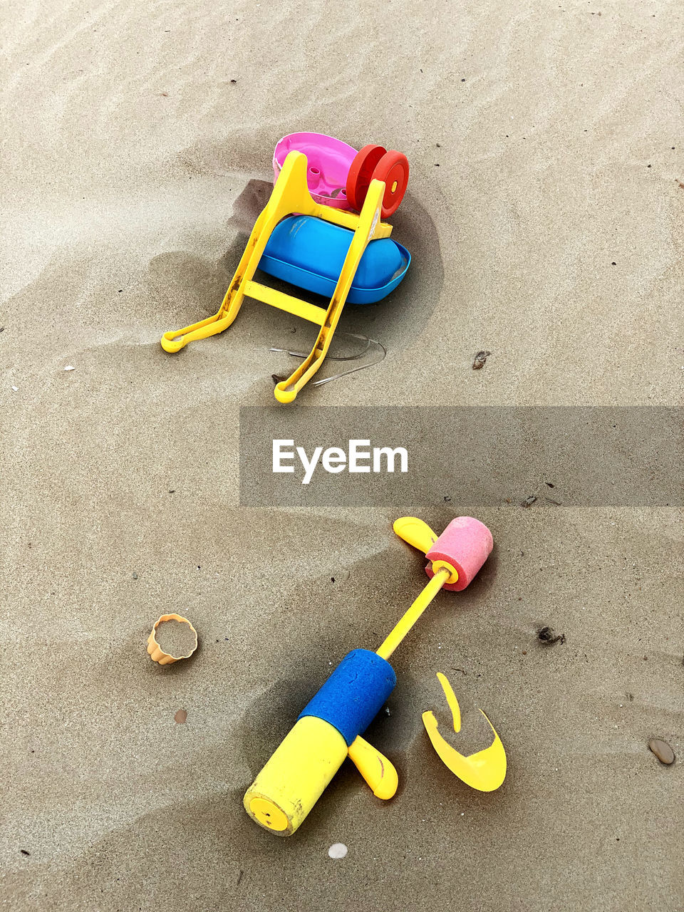 HIGH ANGLE VIEW OF PLASTIC TOY ON SAND