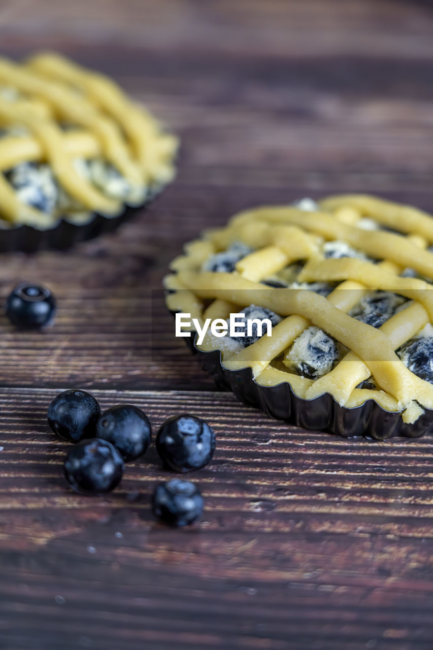 Small cups of delicious blue berry tart or pie on wood table background.