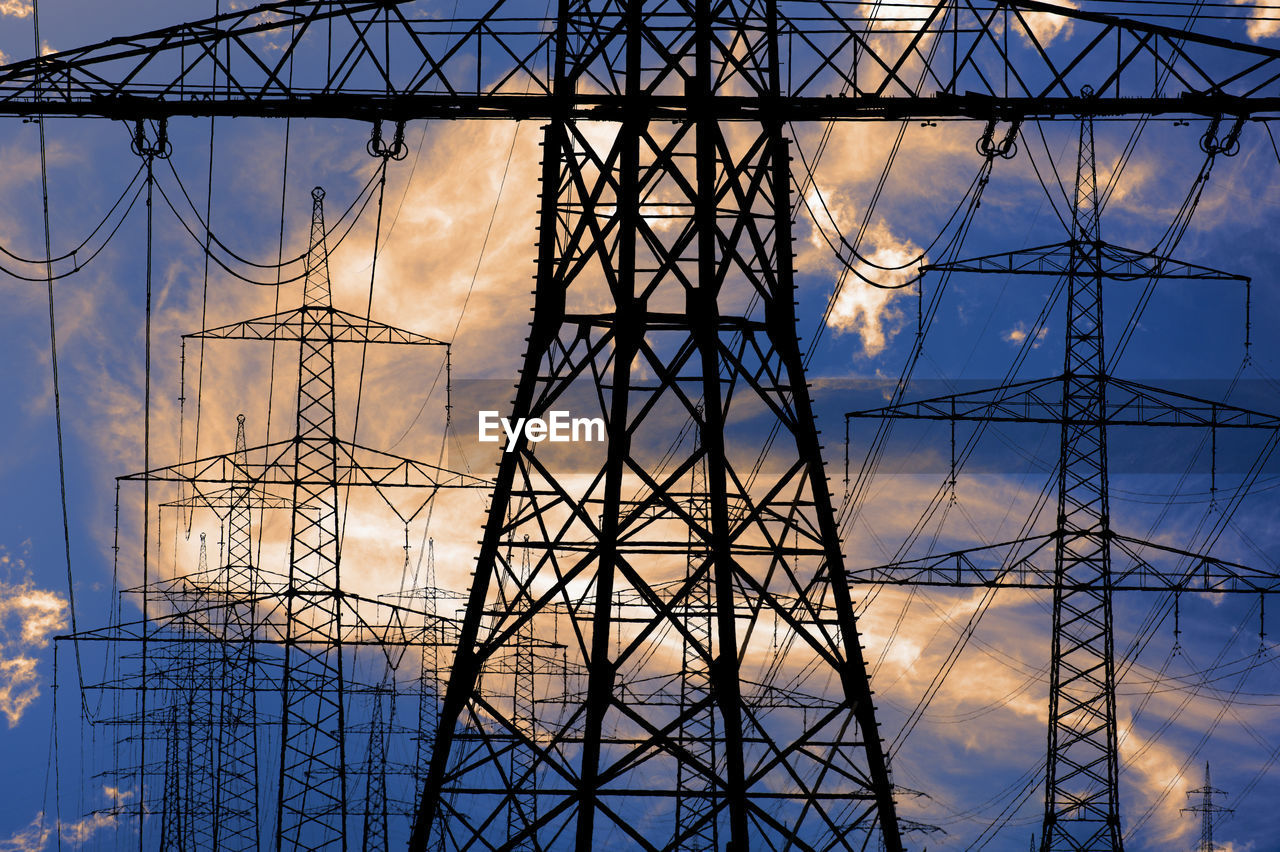 Low angle view of electricity pylon against sky during sunset