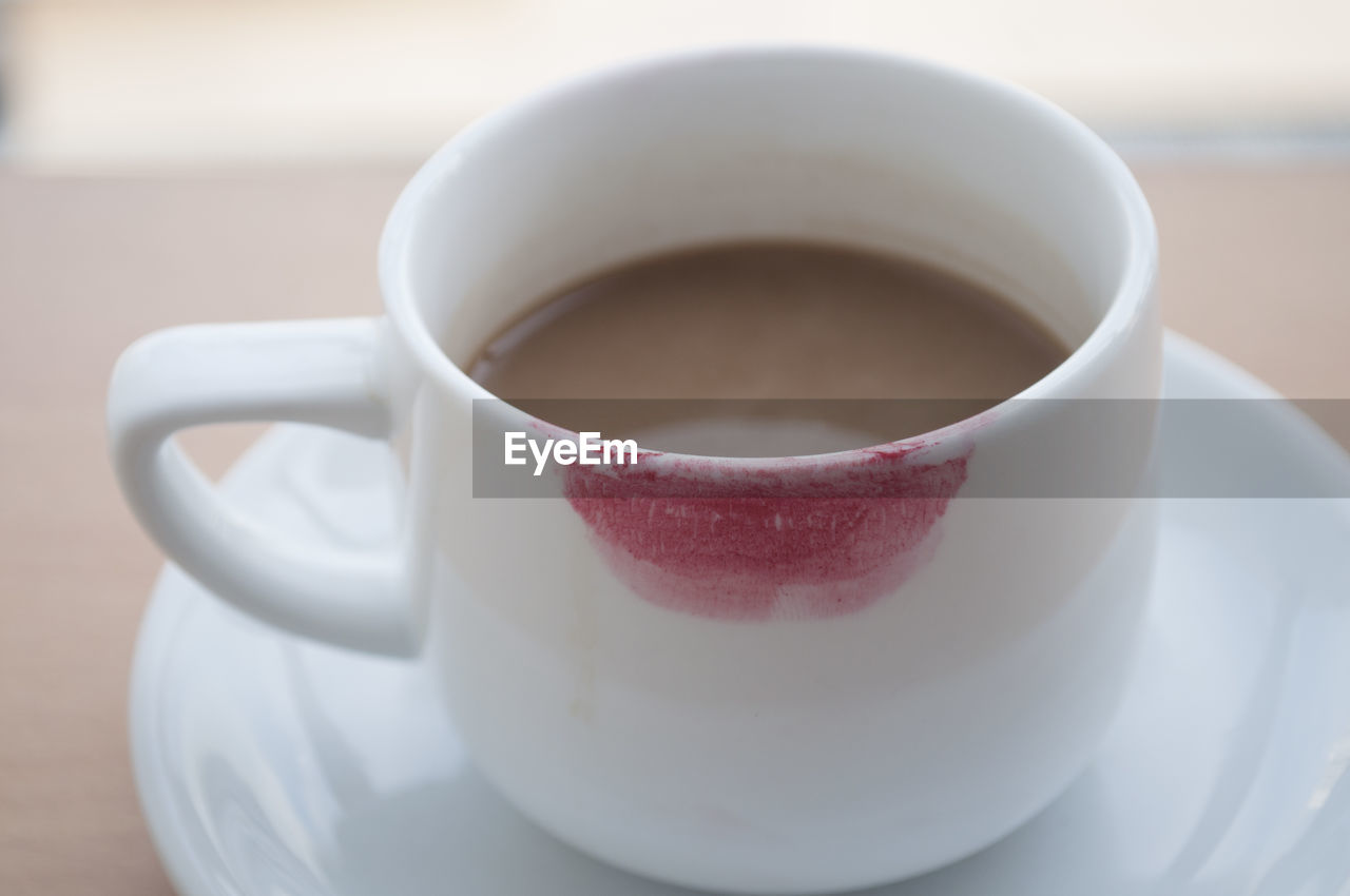Close-up of red lipstick on coffee cup
