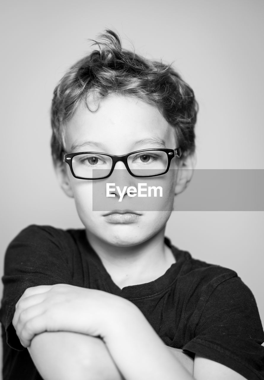 Portrait of boy wearing eyeglasses against gray background