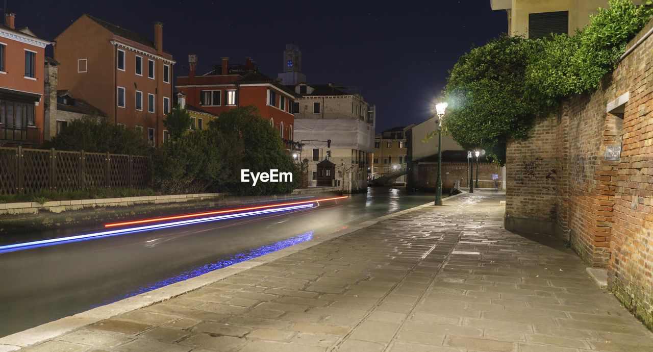 Light trails on road by houses at night
