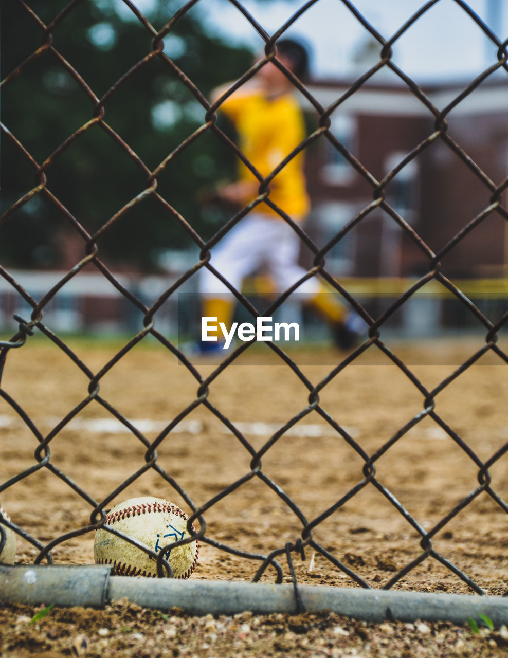 Close-up of baseball seen through chainlink fence