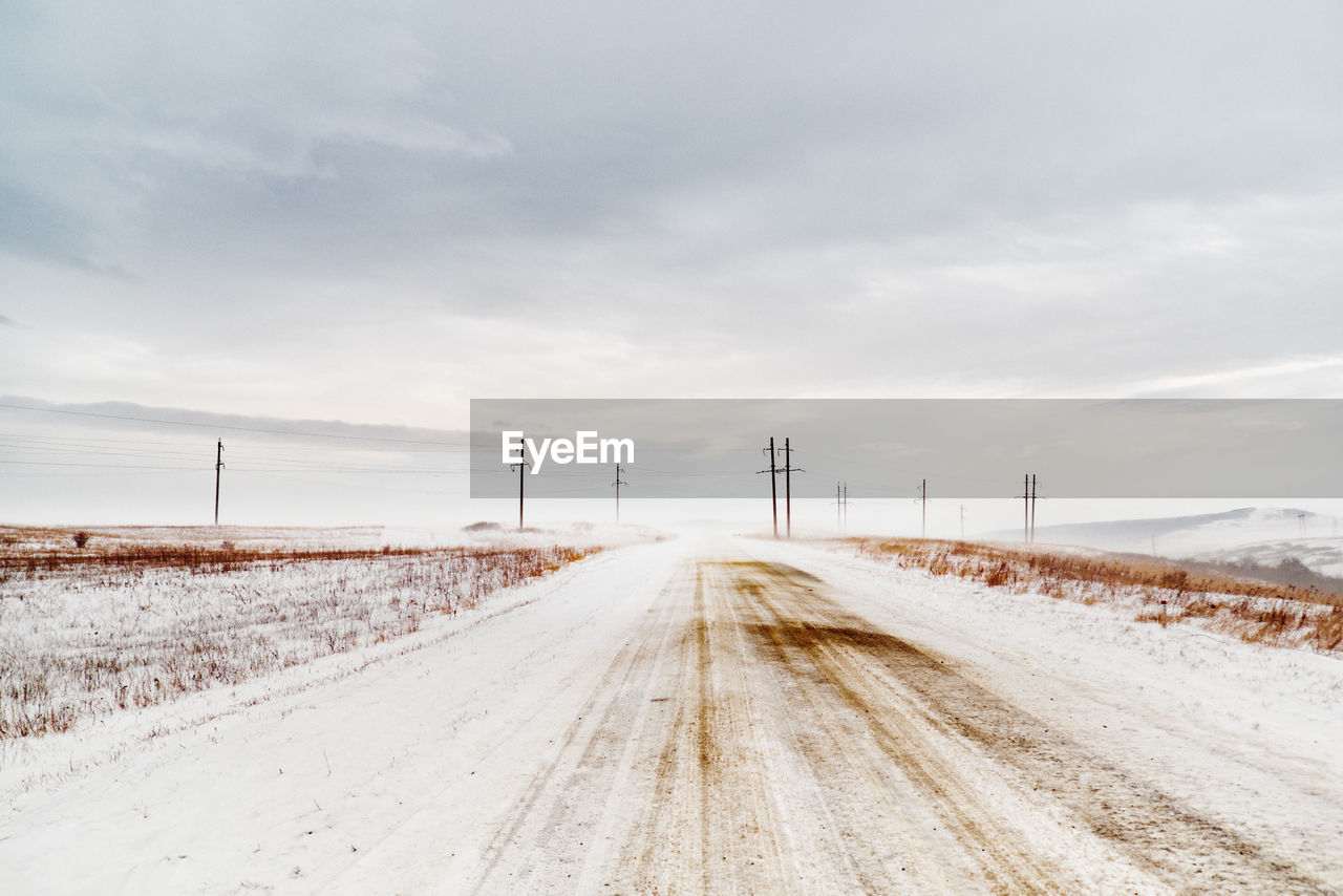 Empty road against cloudy sky in winter