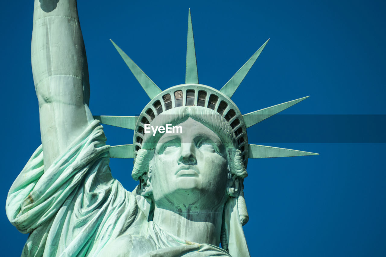 Low angle view of statue of liberty against blue sky