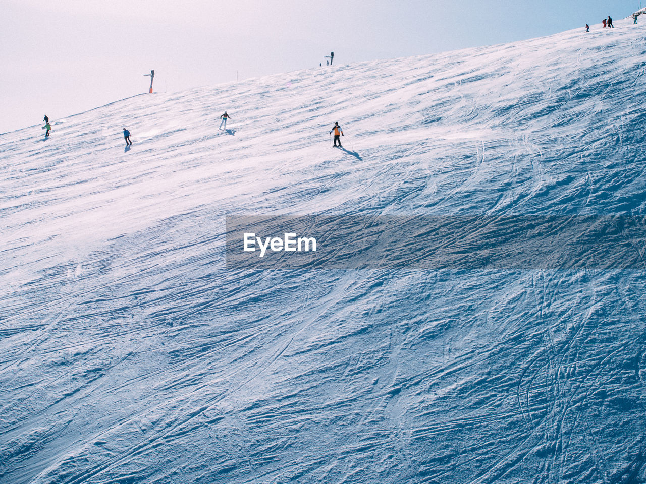 People skiing  on snow covered landscape against sky