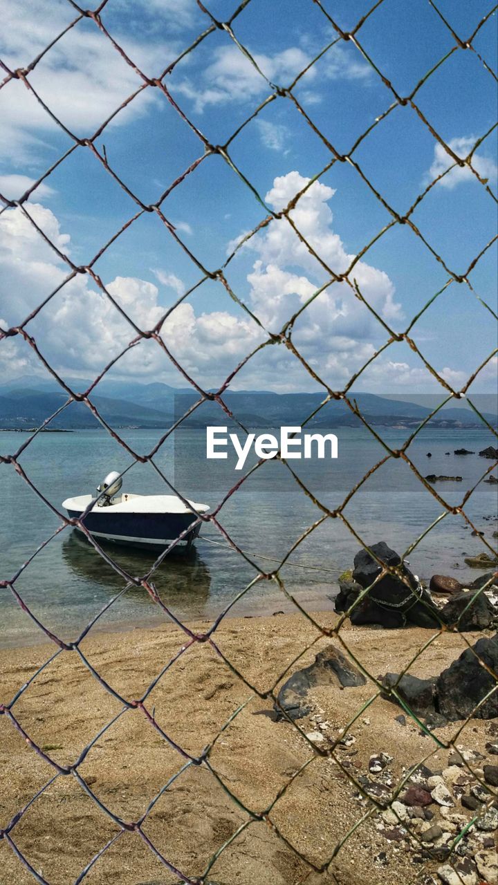 VIEW OF SEA SEEN THROUGH CHAINLINK FENCE