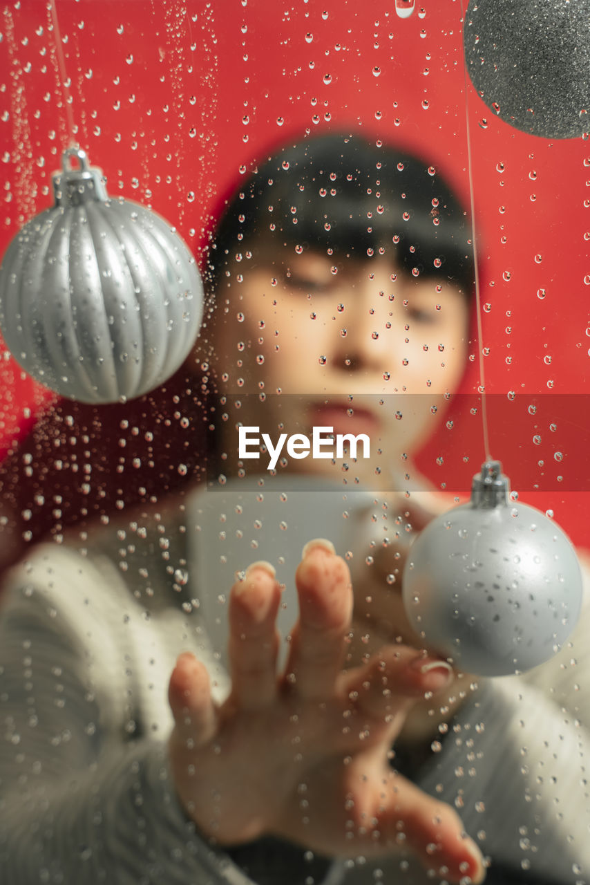 Young woman seen through wet window