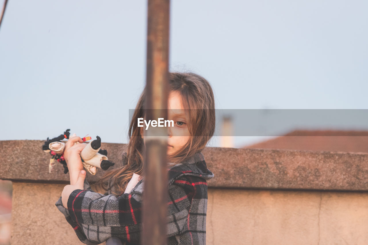 PORTRAIT OF GIRL HOLDING CAMERA AGAINST SKY