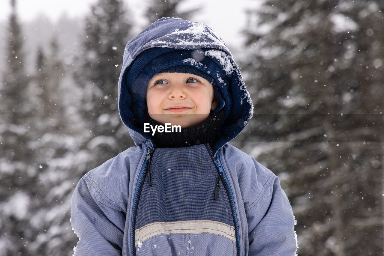 portrait of smiling young woman standing on snow