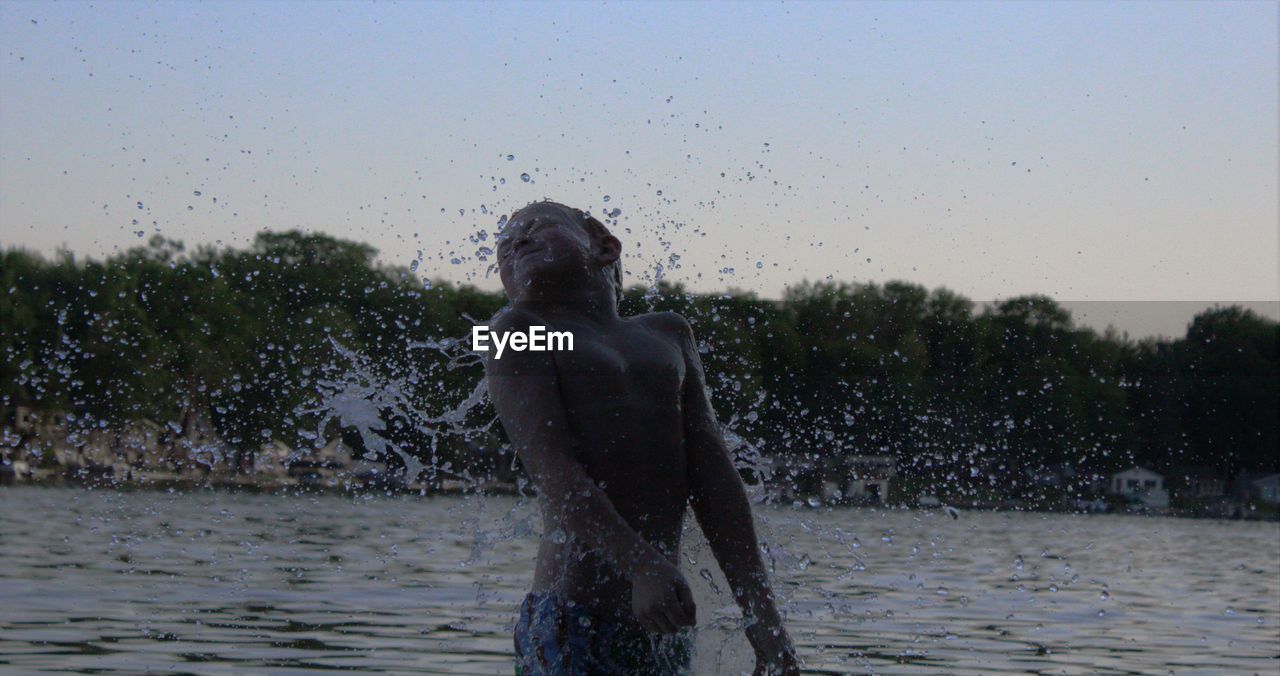 Boy playing in lake against clear sky