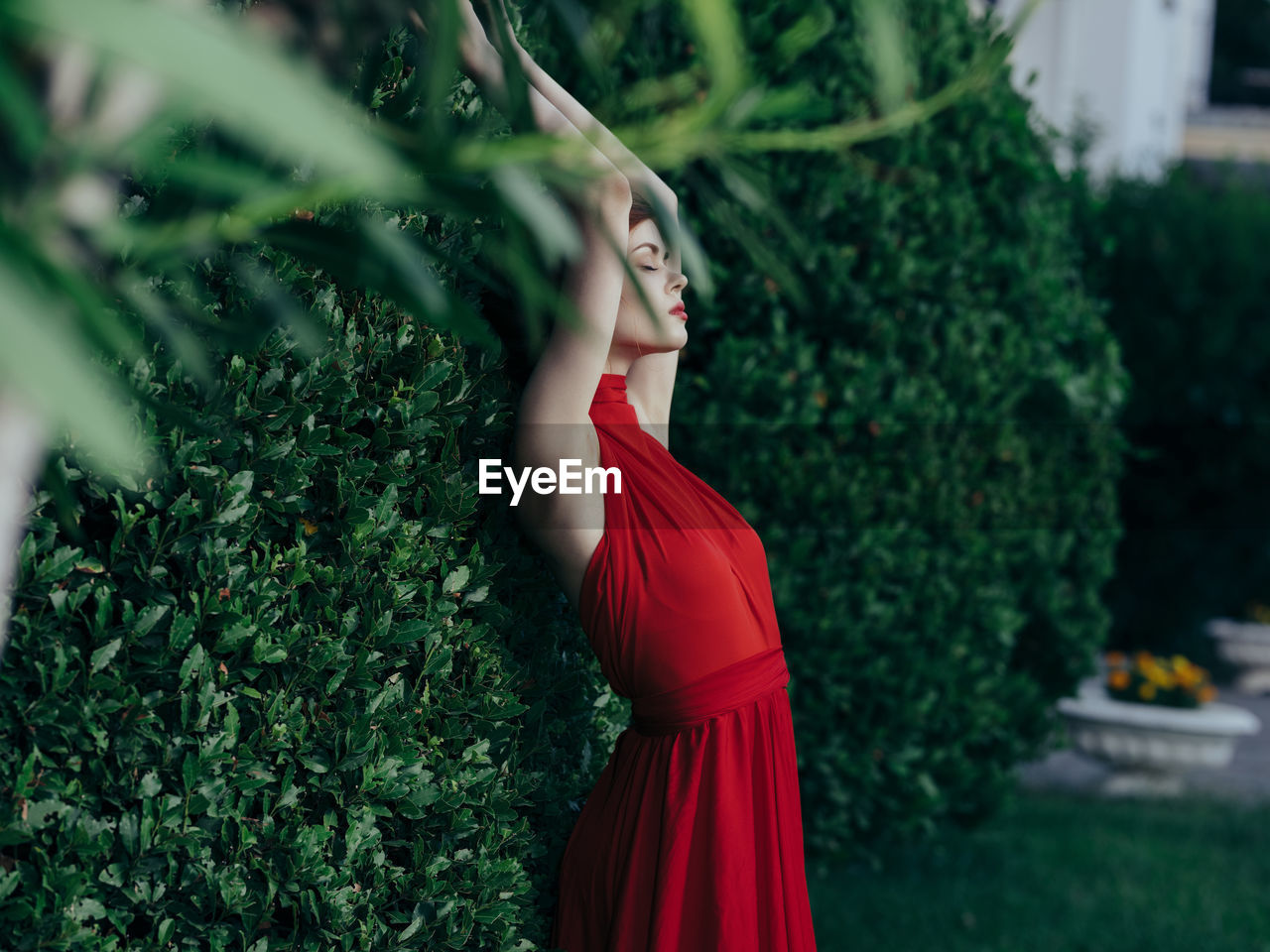 Side view of young woman standing by plants