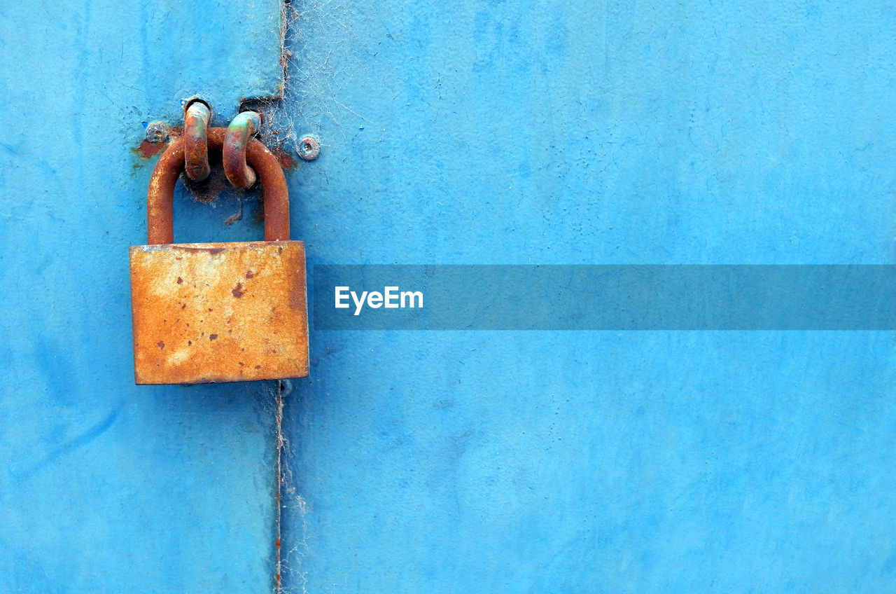 Close-up of blue doors and orange padlock