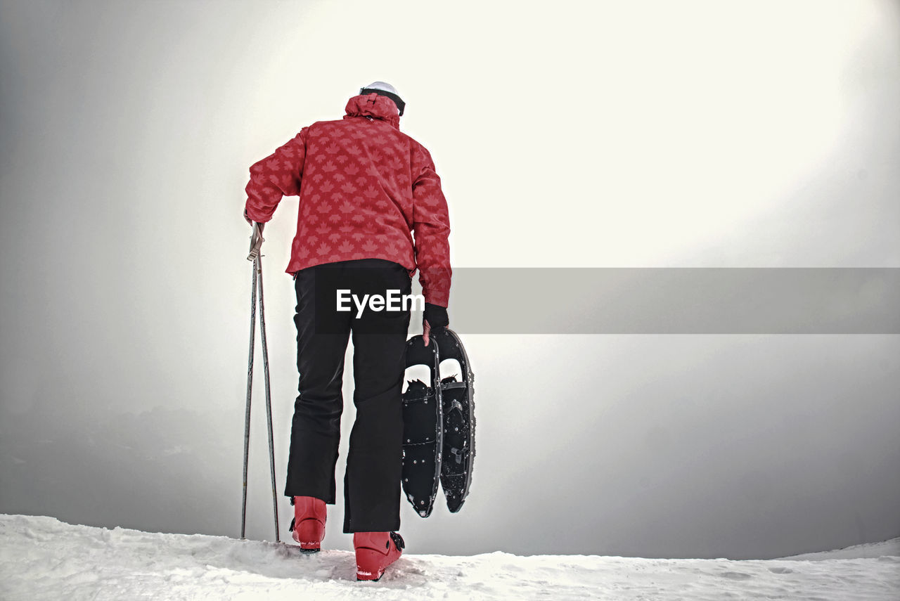 Man with snowshoes in the mountains in winter. man holding sticks walks through snow. winter ascent