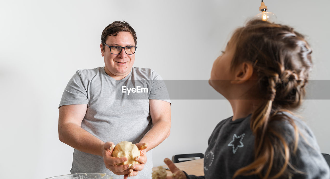 Father feeling playful with his caucasian little daughter, while preparing homemade dough 