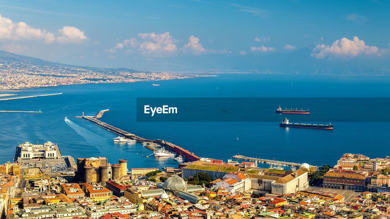 HIGH ANGLE VIEW OF BUILDINGS AND SEA AGAINST SKY