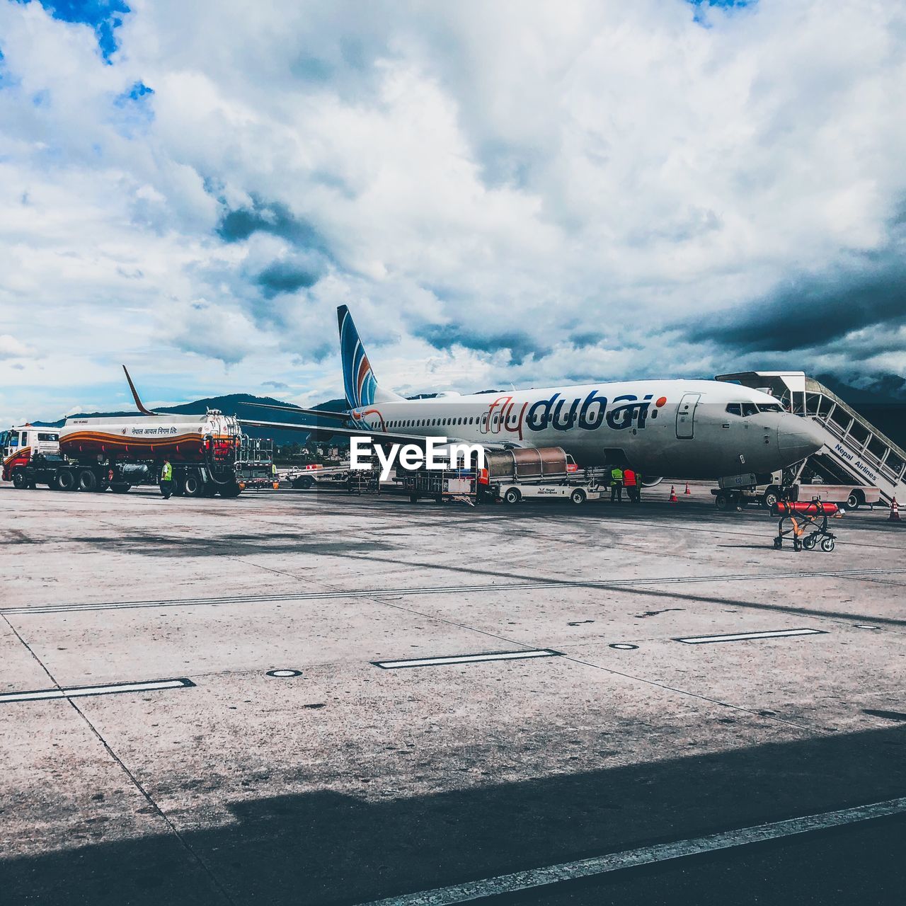 AIRPLANE ON AIRPORT RUNWAY AGAINST CLOUDY SKY