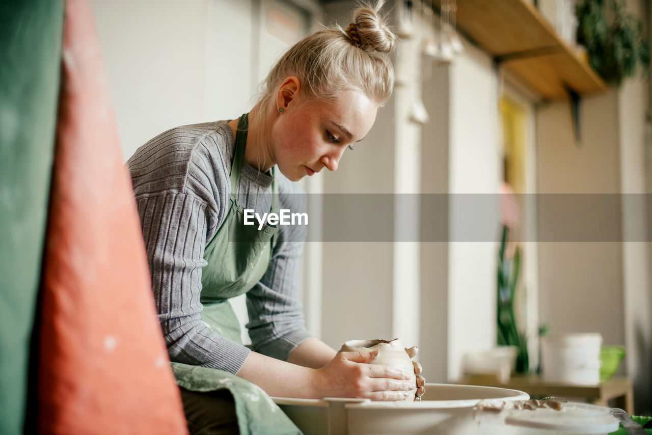 Young woman learning pottery on a potter's wheel