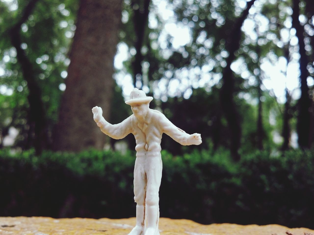 Close-up of figurine against blurred trees