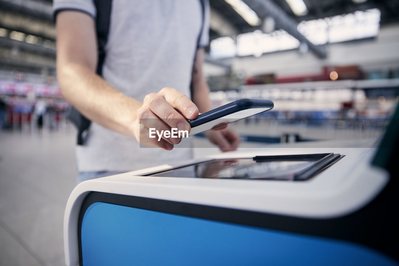 Hand of man during using self service check-in. passenger scanning ticket on smart phone at airport.