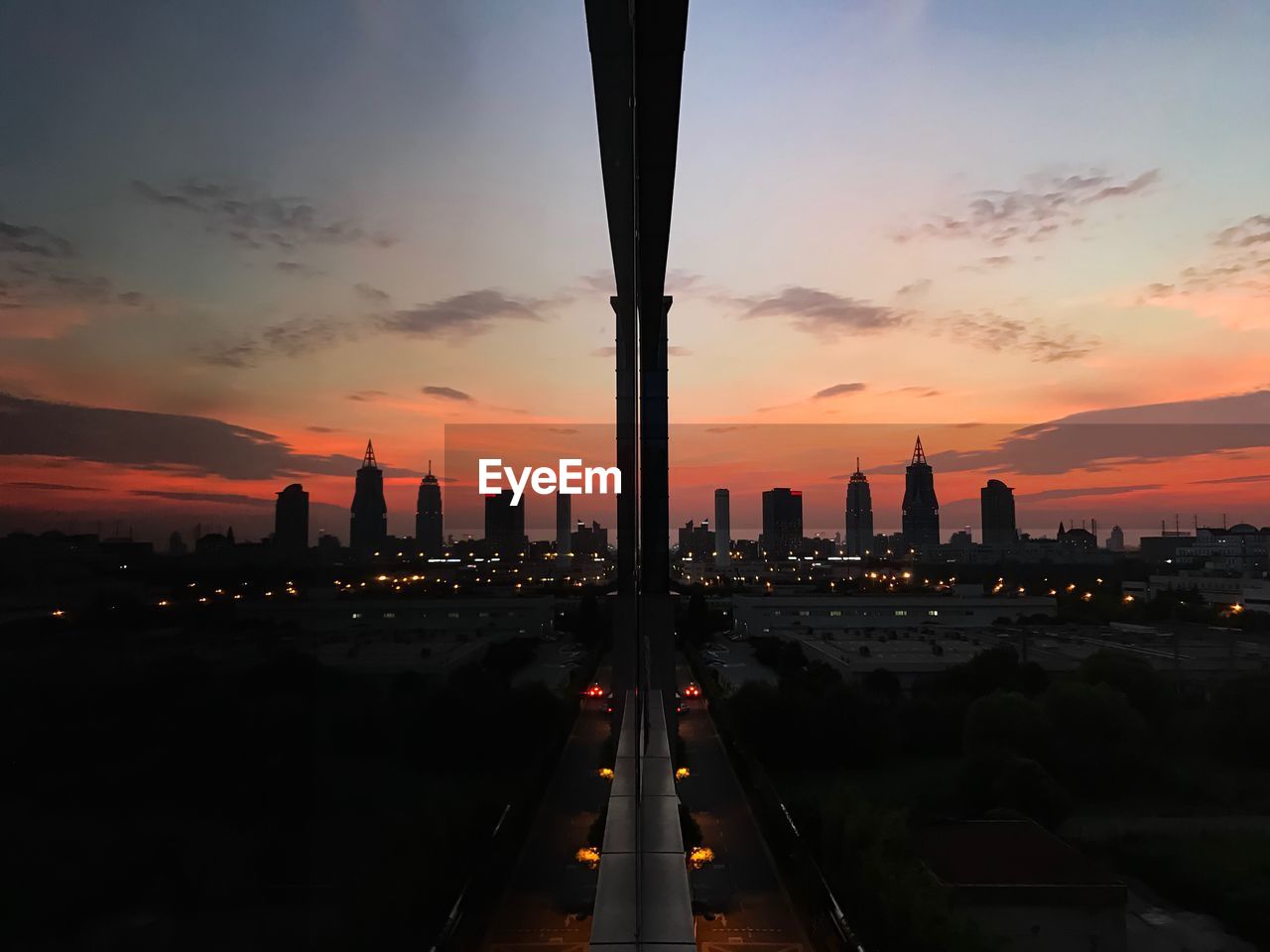 Silhouette city reflecting on glass window during sunset