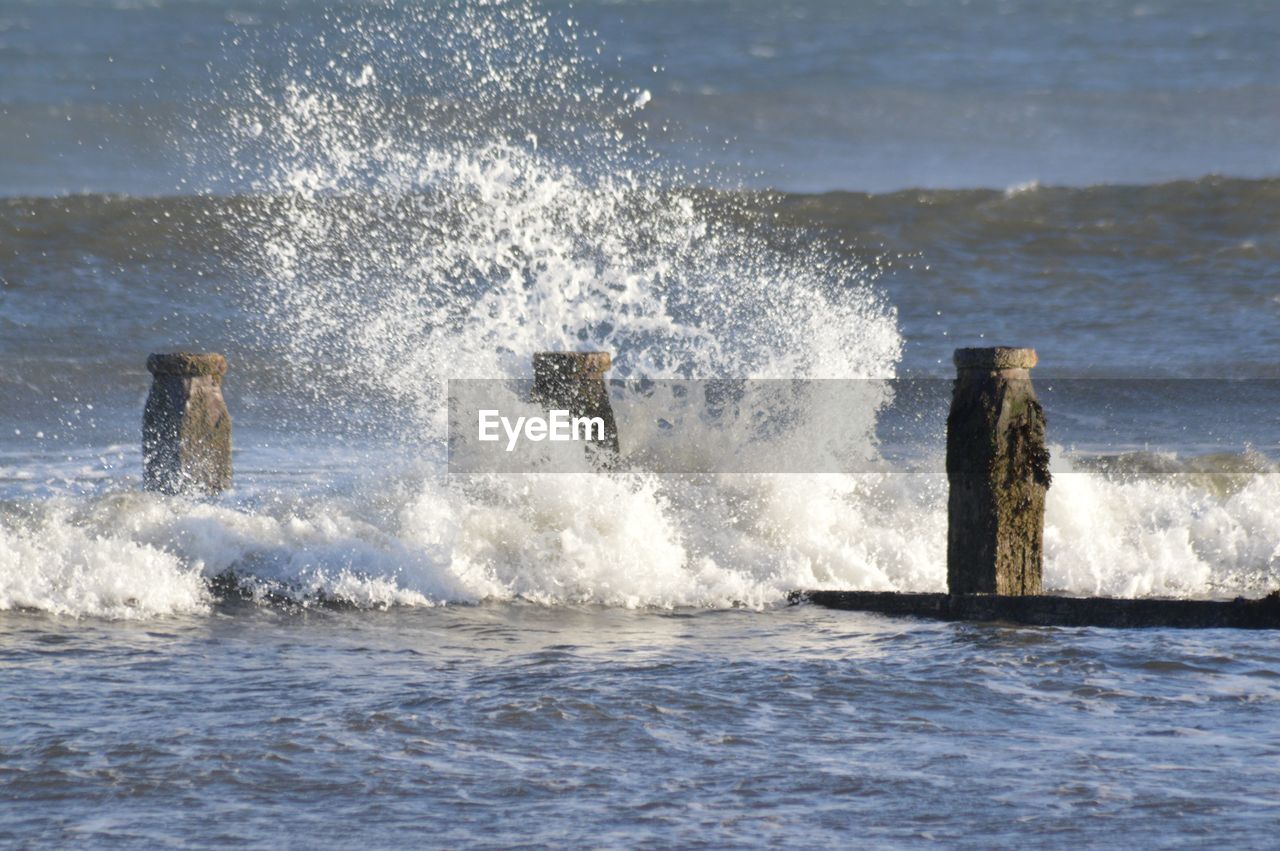 WATER SPLASHING IN SEA AGAINST SKY