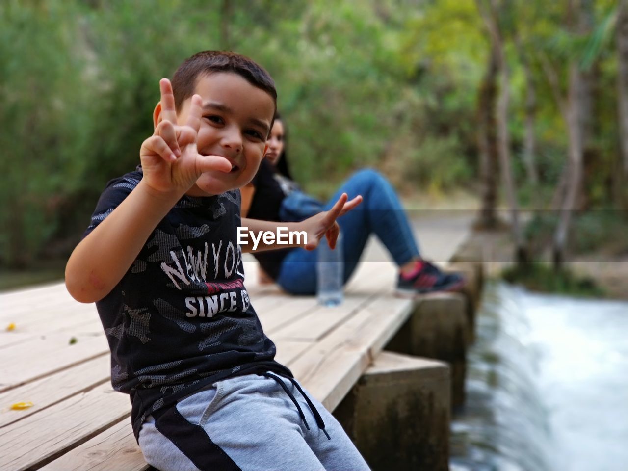 Portrait of smiling boy sitting with mother on pier