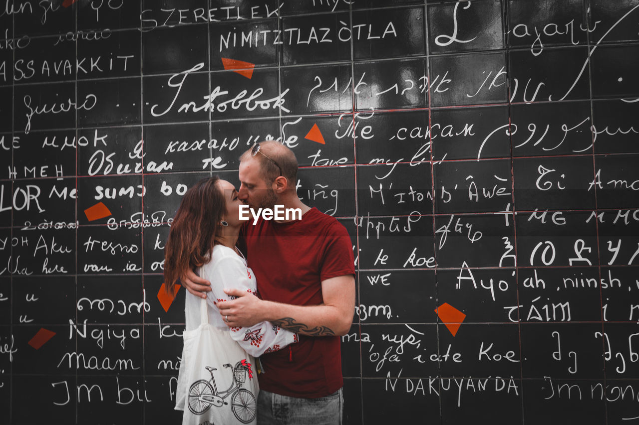 Couple kissing against blackboard with text