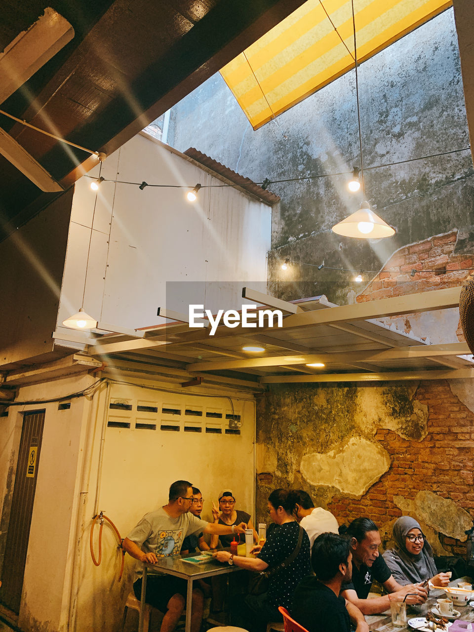 PEOPLE SITTING IN ILLUMINATED RESTAURANT