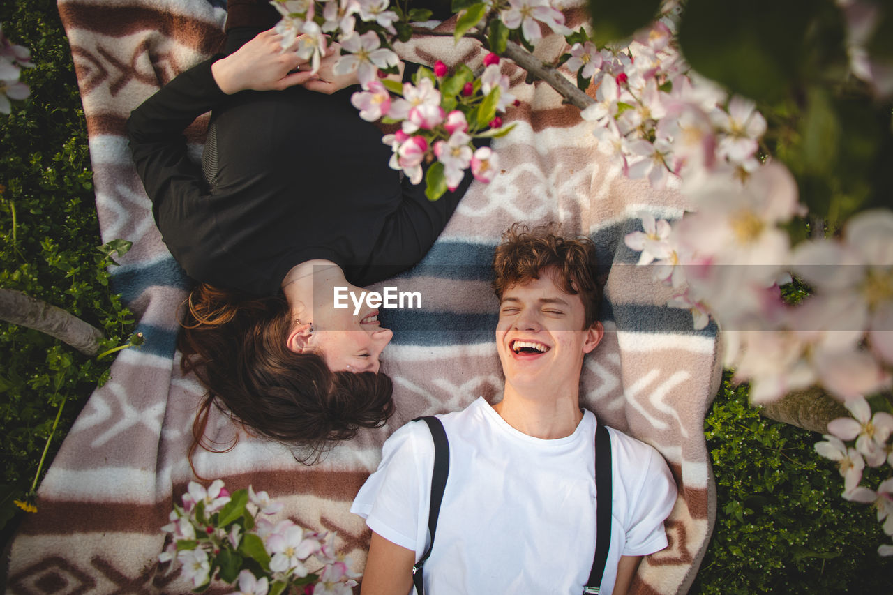 Strong love between two young people lying on a blanket under apple trees. candid portrait of couple