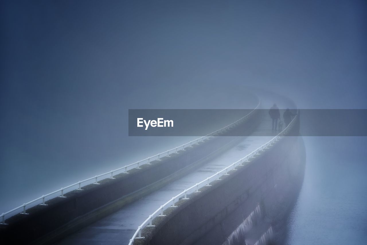 Aerial view of illuminated bridge against blue sky