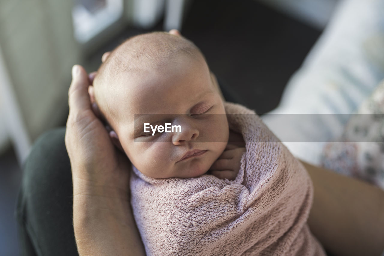 Cropped hands of mother holding newborn daughter