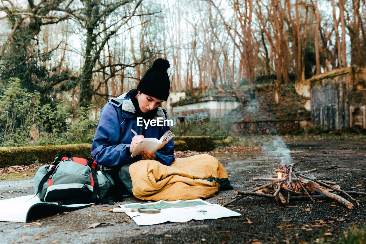 Young female backpacker making notes at campfire