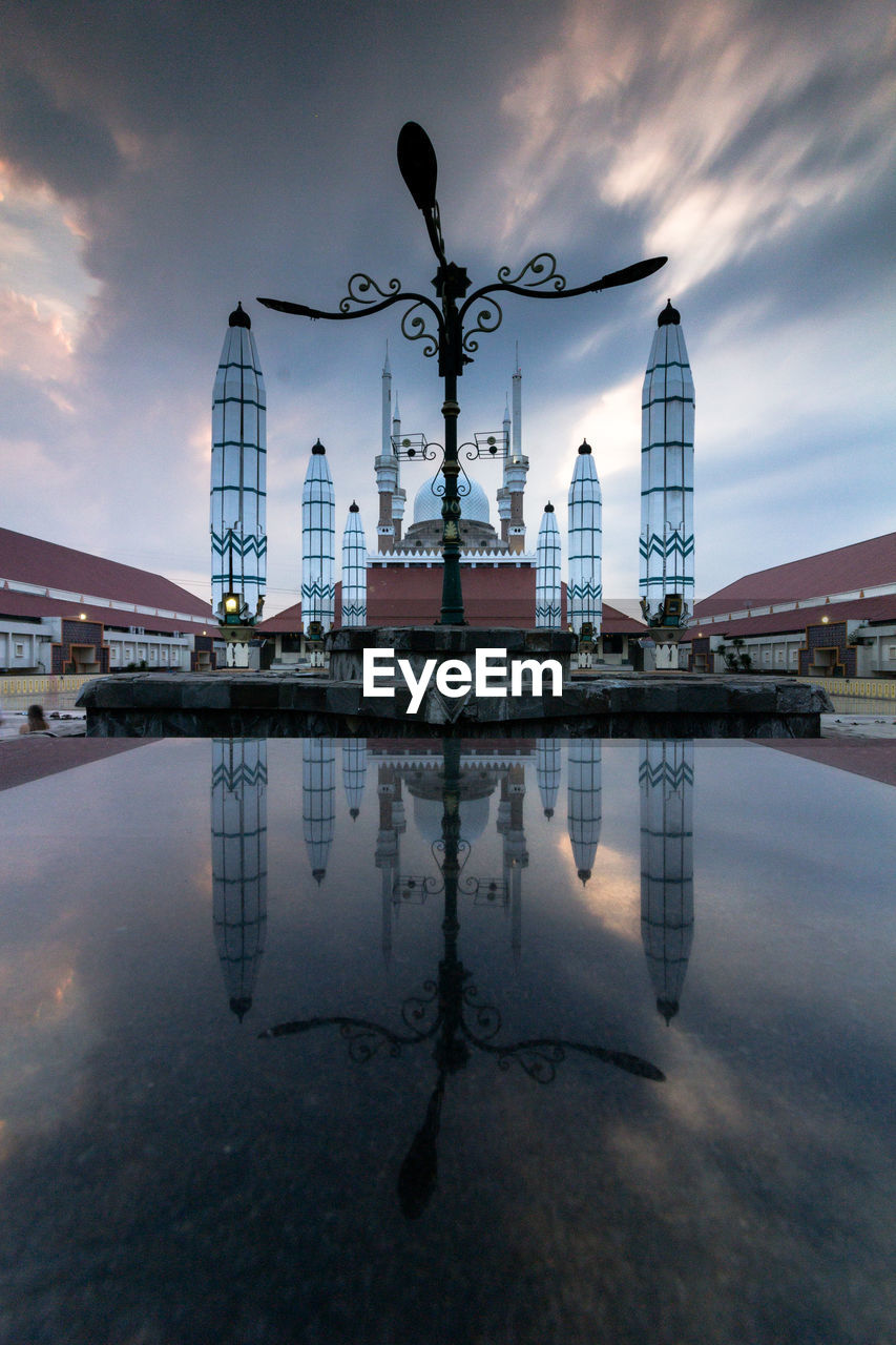 REFLECTION OF BUILDINGS IN PUDDLE AGAINST SKY