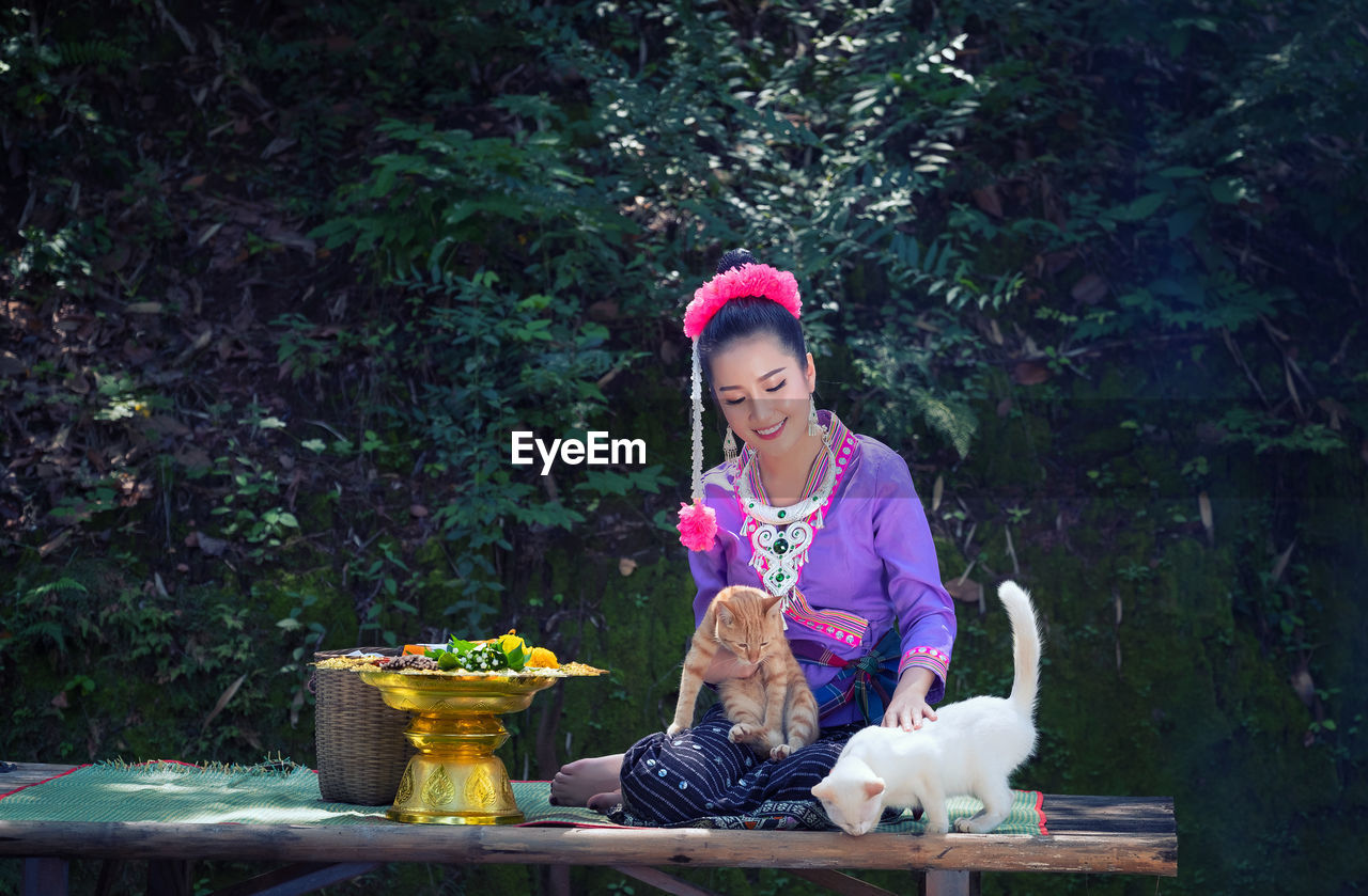 Woman with cats sitting on table against trees