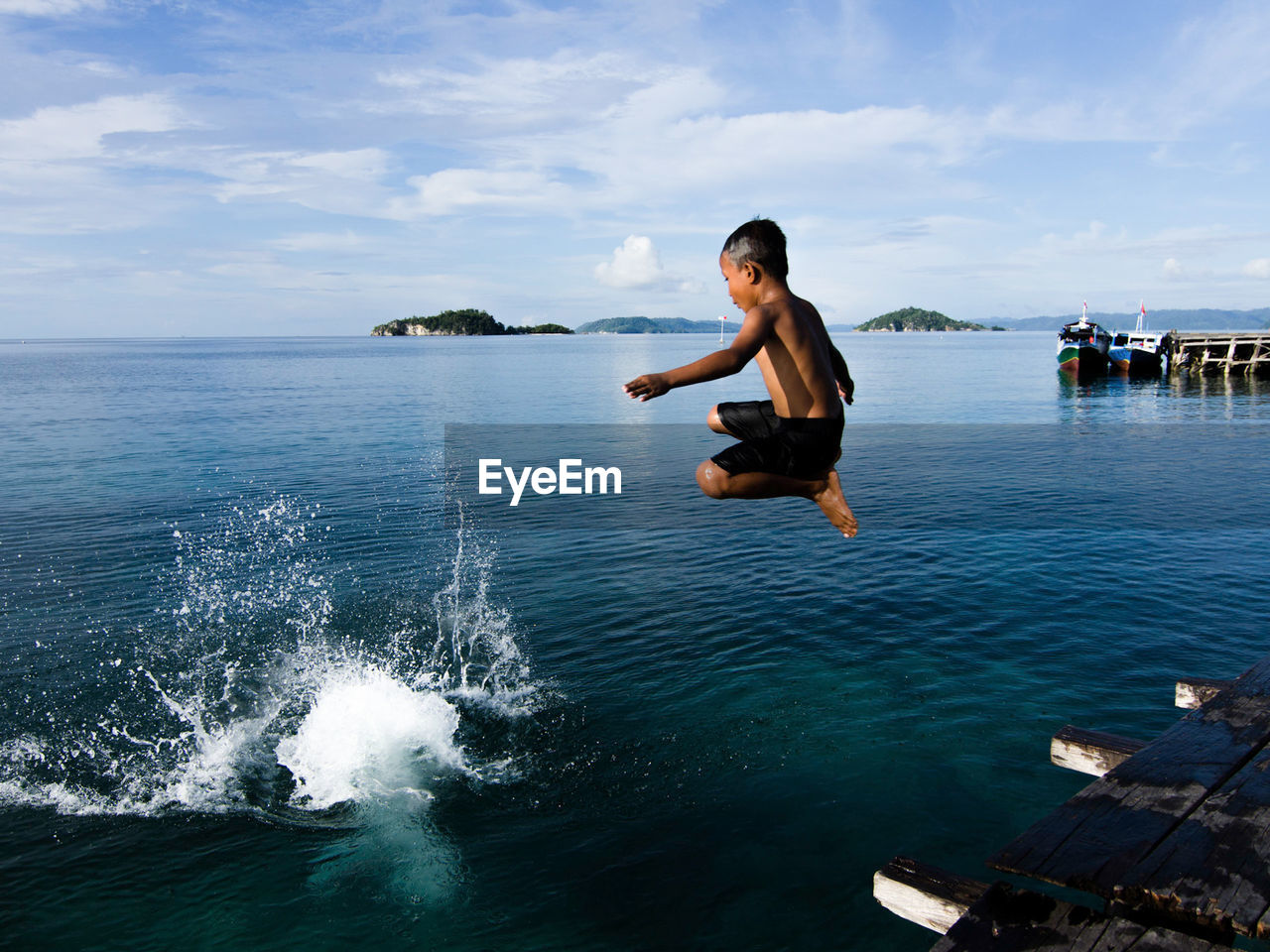 Boy jumping into sea against sky